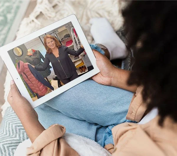 An over-the-shoulder shot of a woman watching a Dressing Well Method Self-Study video on an iPad.